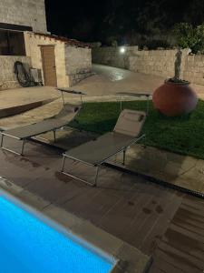 a pool with two chairs and a table next to it at Softades Cottage in Omodos