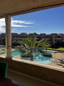 a view of a pool from a window at Appartement golf prestigia in Marrakesh