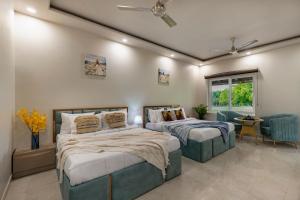 a bedroom with two beds and a chair and a window at Elivaas Enchantia Luxury 6BHK Villa with Pvt Pool in Gurgaon in Bhundsi