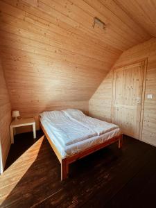 ein Schlafzimmer mit einem Bett in einem Holzzimmer in der Unterkunft Domki Białe Zacisze in Mielenko