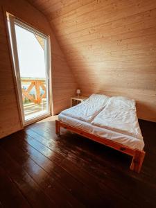 a bed in a room with a large window at Domki Białe Zacisze in Mielenko