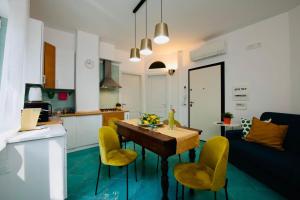 a kitchen and living room with a table and yellow chairs at Amalfia Apartments in Amalfi