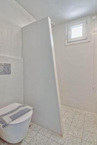 a white bathroom with a toilet and a window at Hotel Mantalena in Antiparos Town