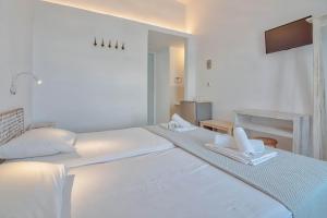 a white bedroom with a large bed with two towels at Hotel Mantalena in Antiparos Town