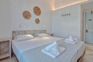 a white bedroom with two beds with towels on them at Hotel Mantalena in Antiparos Town