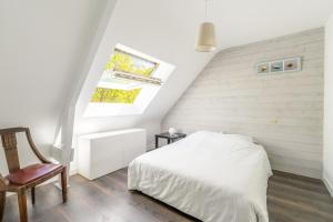 a white bedroom with a bed and a chair at Bel appartement à 300m des plages in Carnac