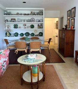 ein Wohnzimmer mit einem Tisch, Stühlen und Regalen in der Unterkunft Hortensias de jardín in O Grove