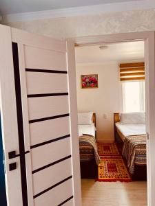 Zimmer mit 2 Betten und einer Schiebetür in der Unterkunft Tumar Guest House in Naryn