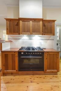 una cocina con horno negro y armarios de madera en Hopkins River Homestead en Allansford