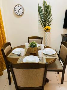 uma mesa de jantar com cadeiras e um relógio na parede em Hello condo em Manilla