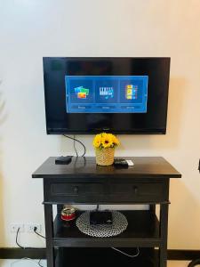 a television on top of a table with flowers on it at Hello condo in Manila