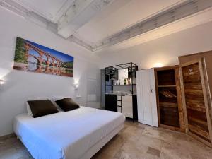 a bedroom with a white bed and a kitchen at Hotel Majestic in Nîmes