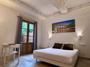 1 dormitorio con cama, mesa y ventana en Hotel Majestic en Nimes