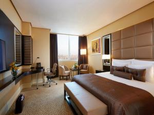 um quarto de hotel com uma cama grande e uma secretária em Millennium Hotel & Convention Centre Kuwait em Kuwait