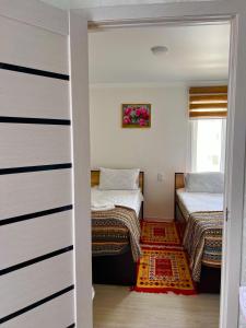 ein kleines Zimmer mit 2 Betten und einem Eingang in der Unterkunft Tumar Guest House in Naryn