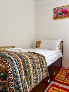 ein Schlafzimmer mit einem Bett mit einer bunten Decke darauf in der Unterkunft Tumar Guest House in Naryn