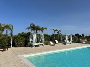 a swimming pool with lounge chairs and palm trees at casa croma in Siracusa