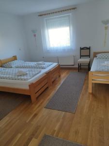 2 Betten in einem Zimmer mit Holzböden und einem Fenster in der Unterkunft Apartments Matijevic in Grabovac