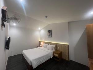 a hotel room with a white bed and a tv at A25 Hotel - 14 Hồ Huấn Nghiệp in Ho Chi Minh City