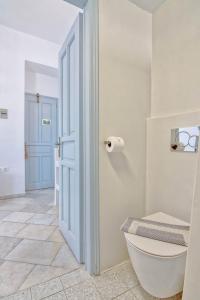 a white bathroom with a toilet and a door at Hotel Mantalena in Antiparos Town
