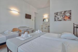 a white room with two beds with towels on them at Hotel Mantalena in Antiparos Town