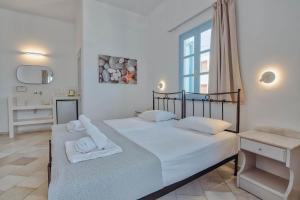 two beds in a white bedroom with a window at Hotel Mantalena in Antiparos Town