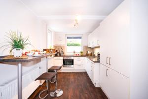 a kitchen with white cabinets and a table and stools at Ferienhaus Auszeit - Wohnung "Strandmuschel" in Grömitz +16 photos
