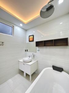 a white bathroom with a tub and a sink at Teky House Huế in Thôn Trường Giang