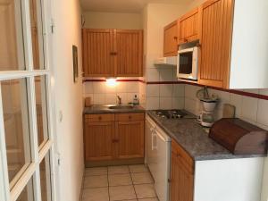 Elle comprend une petite cuisine avec des placards en bois et un évier. dans l'établissement Appartement Montgenèvre, 2 pièces, 6 personnes - FR-1-445-140, à Montgenèvre