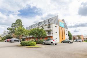 un bâtiment avec des voitures garées dans un parking dans l'établissement Appart'City Classic Nantes - Carquefou, à Carquefou