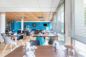 un restaurante con mesas, sillas y paredes azules en Appart'City Classic Nantes - Carquefou en Carquefou