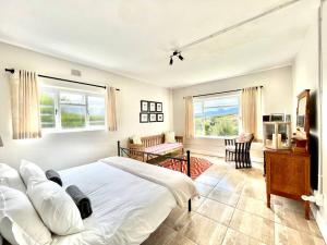 a bedroom with a bed and a desk and windows at Elgin Views Annex in Ouda Brug