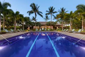a swimming pool with palm trees in the background at INSPIRATION VILLA Inspiring 2BR Kulalani Home with Private Beach Club in Waikoloa