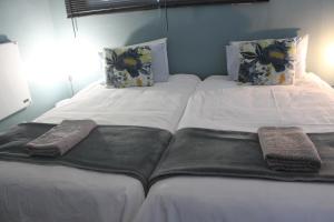2 camas en una habitación con sábanas y almohadas blancas en Berry Lane Guesthouse, en Kroonstad