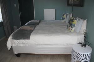 1 dormitorio con 1 cama grande con sábanas y almohadas blancas en Berry Lane Guesthouse, en Kroonstad