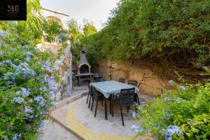 un tavolo e sedie in un giardino fiorito di Spacious Villa with Private Pool & BBQ in St'Pauls by 360 Estates a San Pawl il-Baħar