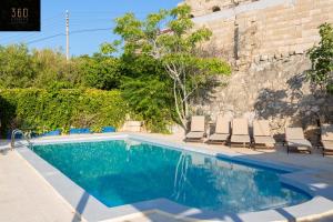 una piscina con sedie a sdraio accanto a un muro di mattoni di Spacious Villa with Private Pool & BBQ in St'Pauls by 360 Estates a San Pawl il-Baħar Altre 37 foto