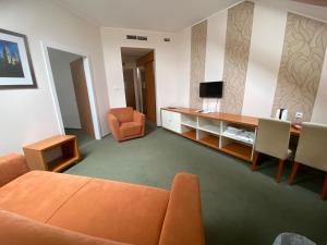 - un salon avec un canapé orange et un bureau dans l'établissement Boutique Hotel Sopianae, à Pécs