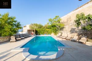 una piscina con sedie a sdraio accanto a un edificio di Spacious Villa with Private Pool & BBQ in St'Pauls by 360 Estates a San Pawl il-Baħar