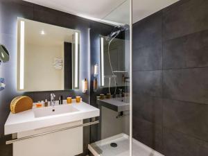 La salle de bains est pourvue d'un lavabo et d'un miroir. dans l'établissement Hôtel Mercure Lyon Centre Lumière, à Lyon