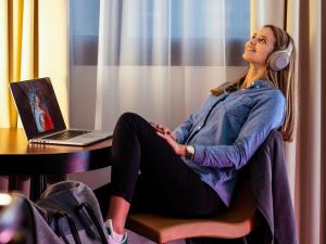 a woman wearing headphones sitting at a table with a laptop at Hôtel Mercure Lyon Centre Lumière in Lyon