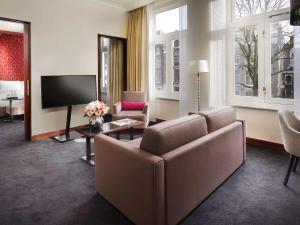 a living room with a couch and a flat screen tv at Sofitel Legend The Grand Amsterdam in Amsterdam