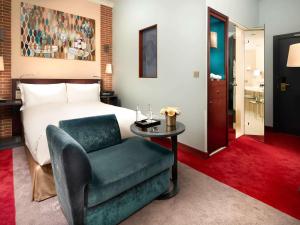 a bedroom with a bed and a chair and a table at Sofitel Legend The Grand Amsterdam in Amsterdam