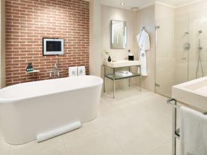 a bathroom with a white tub and a brick wall at Sofitel Legend The Grand Amsterdam in Amsterdam