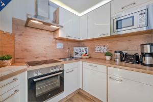 una cocina con armarios blancos y fregadero en Villa Luna Ferienwohnung Achterdeck, en Ahlbeck