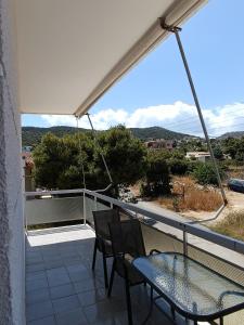 a patio with two chairs and a glass table on a balcony at GOLDEN BEACH in Souvala