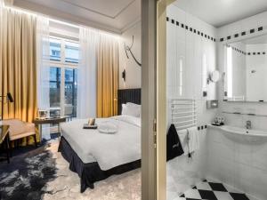 a bedroom with a bed and a bathroom with a sink at Hotel Century Old Town Prague - MGallery Hotel Collection in Prague