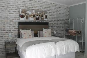 1 dormitorio con 1 cama grande y pared de ladrillo en Berry Lane Guesthouse, en Kroonstad