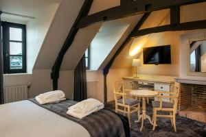 1 dormitorio con cama, mesa y escritorio en Best Western Le Cheval Blanc -Vue sur le port-plein centre ville en Honfleur