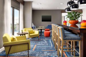 a lobby with chairs and a bar with a television at Hampton Inn Laredo in Laredo